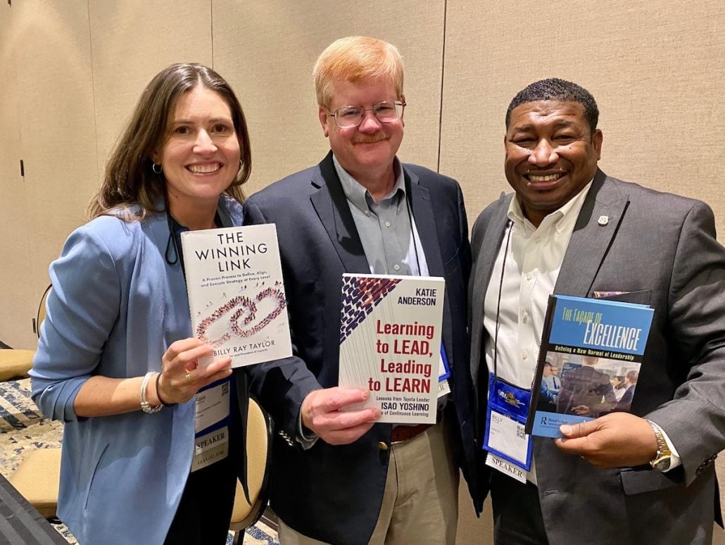 Add caption: Katie Anderson, John Dyer, and Billy Ray Taylor with our books at the AME Conference in 2022.